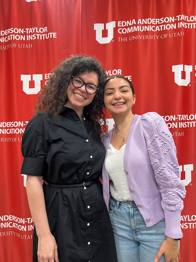 Undergraduate student Jasmine Agular and her Thesis Mentor Assistant Professor Leandra Hernandez smiling together in front of a red Univerisy of Utah backdrop