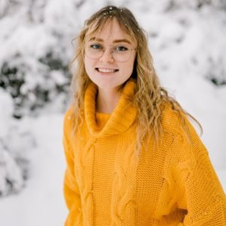 Maggie in a snowy background wearing a yellow sweater